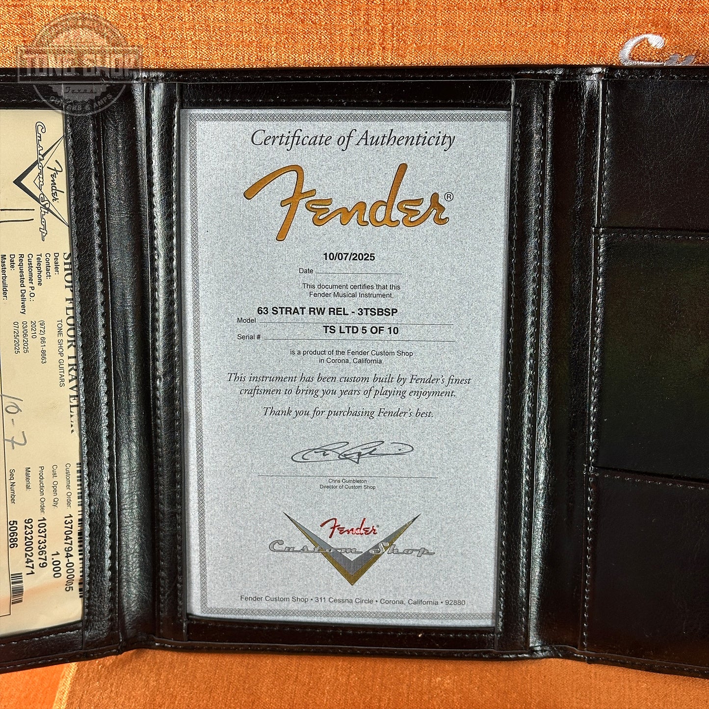 Fender certificate of authenticity in a black leather holder on an orange background