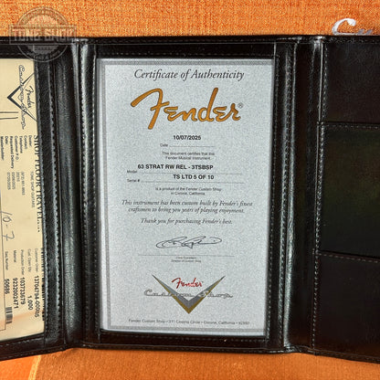 Fender certificate of authenticity in a black leather holder on an orange background
