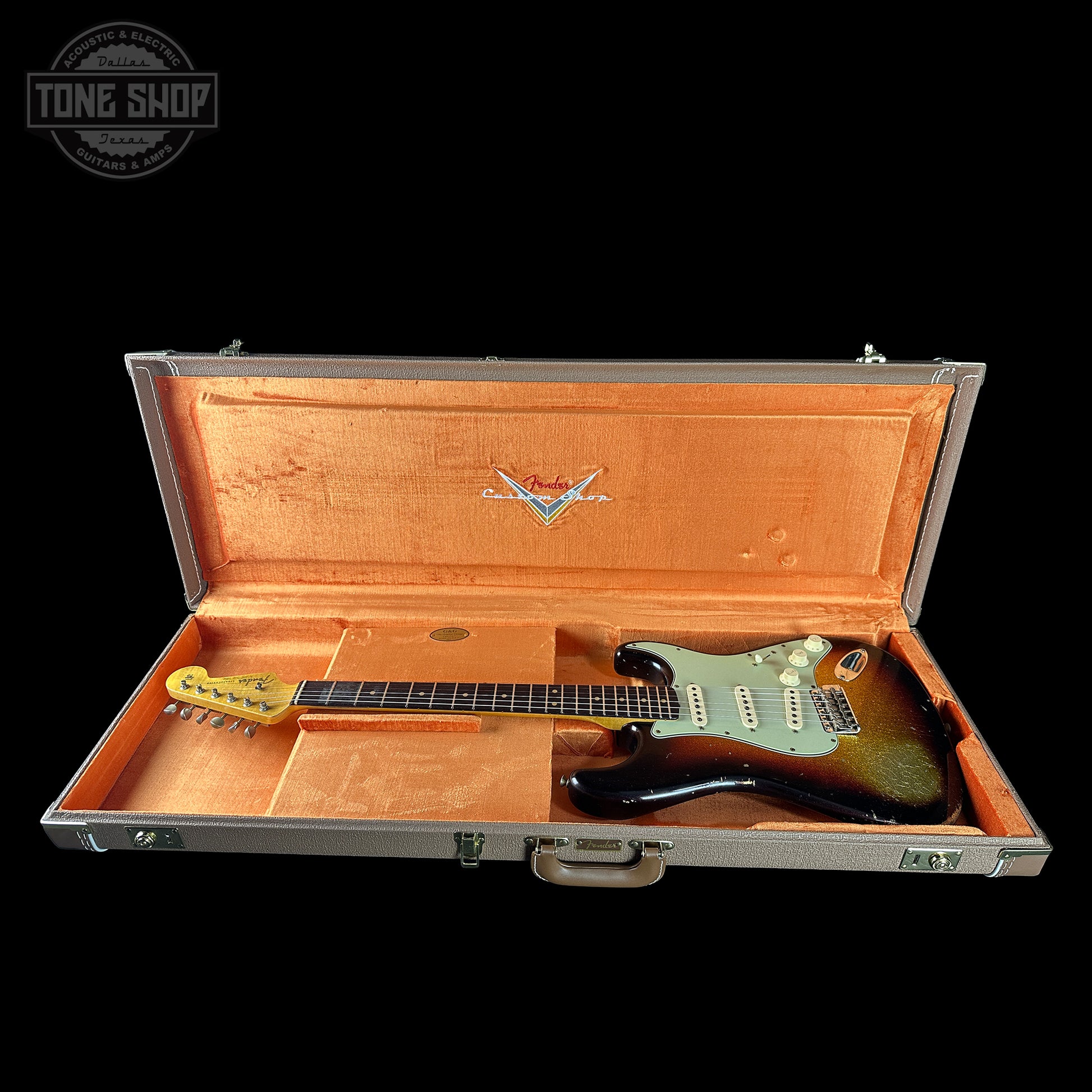 Guitar in an open case with a visible brand logo on a black background