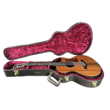 Acoustic guitar in a black case with pink interior on a white background
