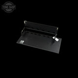 A black metal mounting bracket or shelf support with pre-drilled holes, shown at an angle on a solid black background. A small white Tone Shop sticker is visible on the product, and a larger Tone Shop watermark is in the top-left corner.