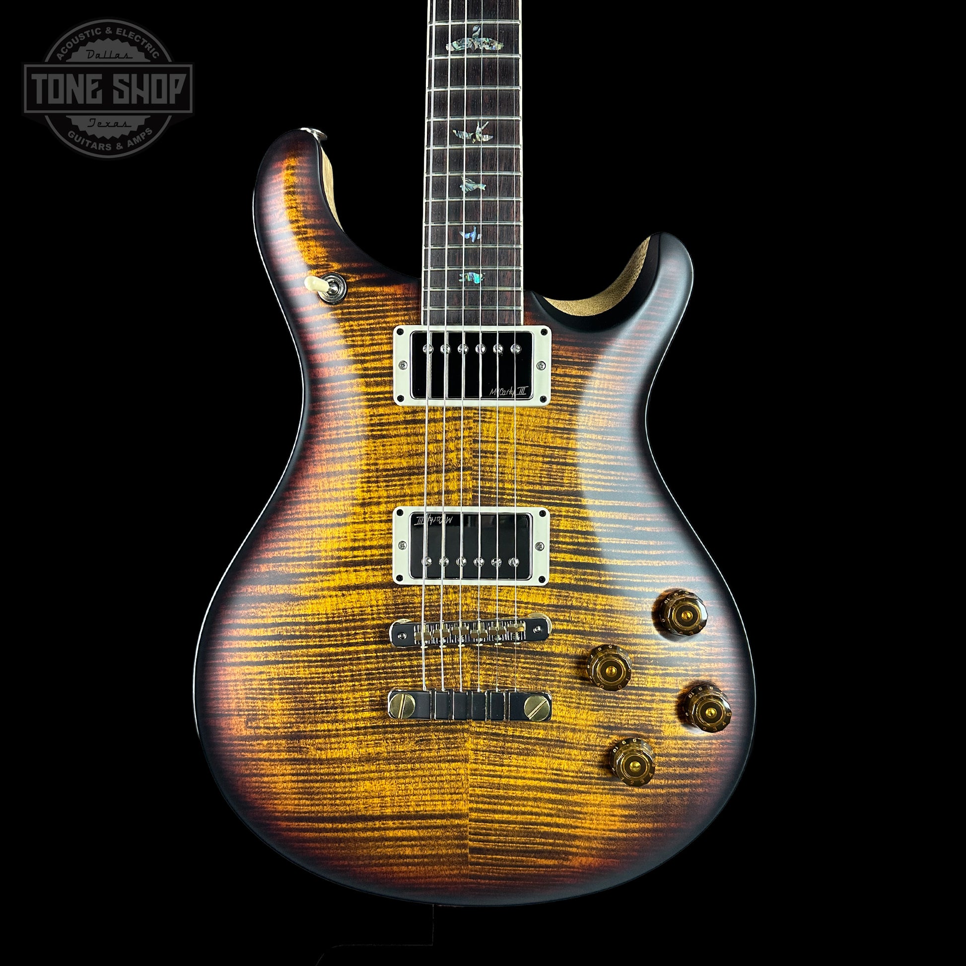 Wooden electric guitar with a black background, featuring the Tone Shop logo.