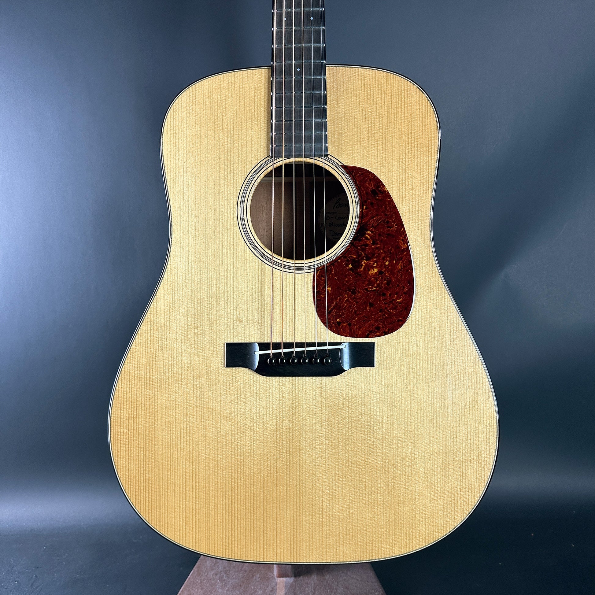 Acoustic guitar on a stand against a dark blue background