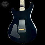 The back of a black electric guitar with a satin black finish, featuring gold hardware and a silver pickguard, shown against a solid black background.
