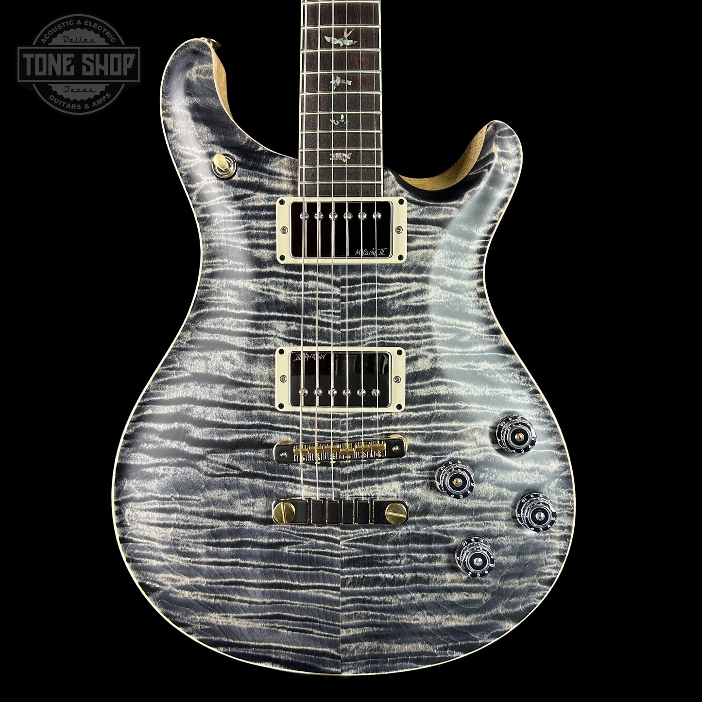 Electric guitar with a unique pattern on the body against a black background, featuring the Tone Shop logo.