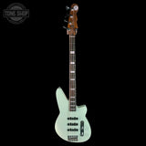 Electric bass guitar with a light green body on a black background, featuring the Tone Shop logo.