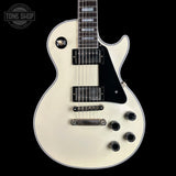 White electric guitar with black details on a black background, featuring 'Tone Shop' branding.