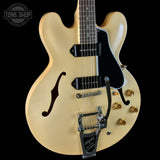 A cream-colored semi-hollow electric guitar with a black pickguard, chrome hardware, and gold-toned controls, shown against a solid black background. A Tone Shop watermark is visible in the top-left corner.