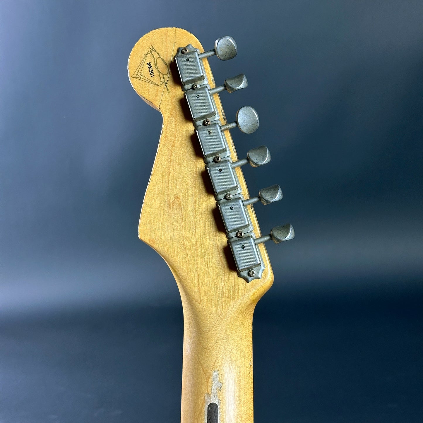 Guitar headstock with tuning pegs on a dark blue background