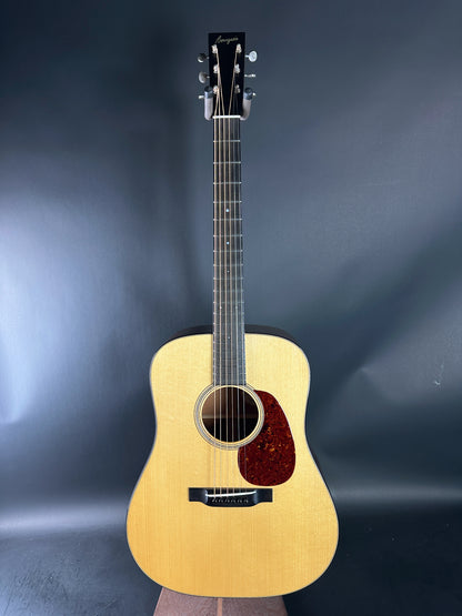 Acoustic guitar with a wooden body and dark pickguard on a blue gradient background