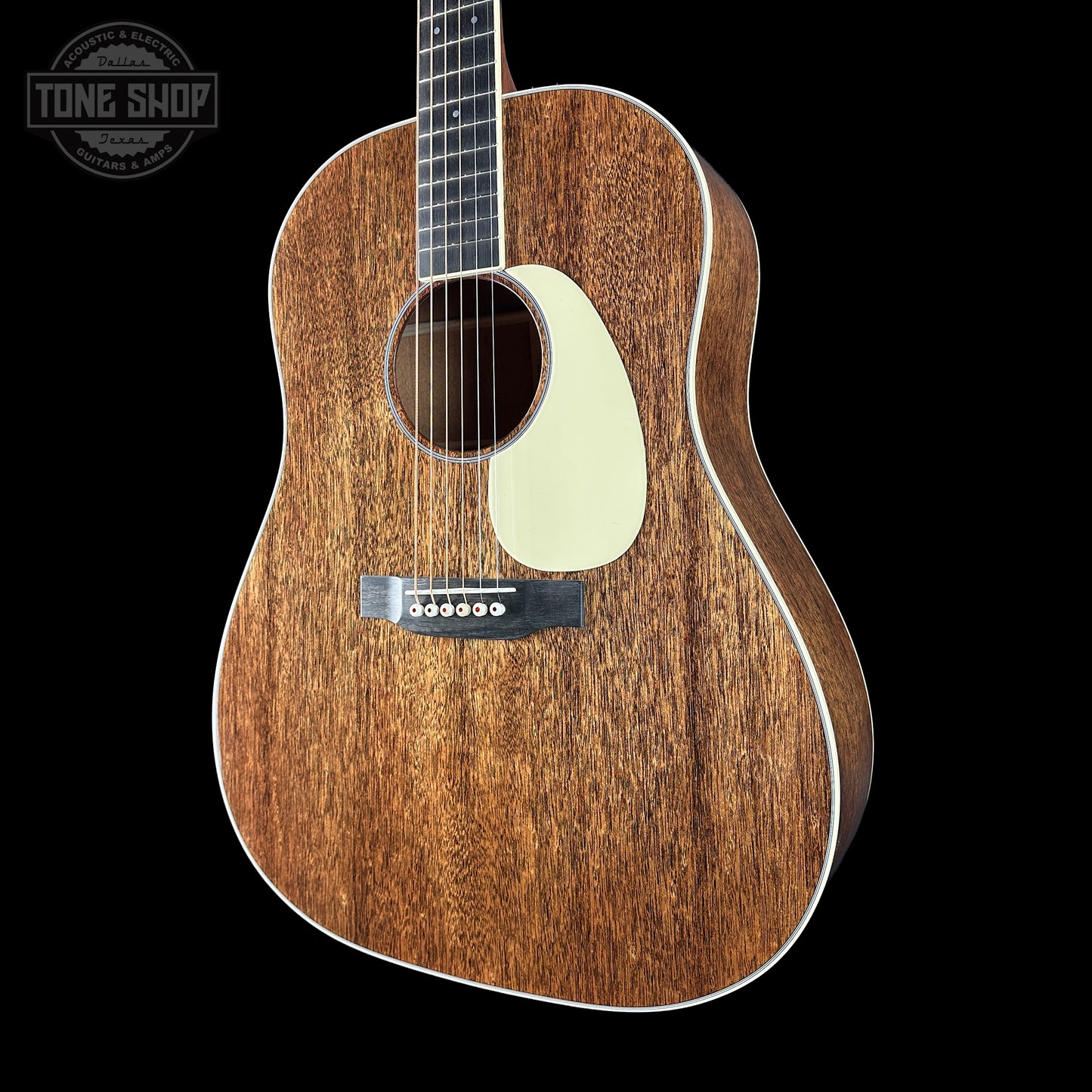 Acoustic guitar with a dark wood finish on a black background, featuring the Tone Shop logo.
