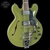 Green electric guitar with a black pickguard on a black background, featuring the Tone Shop logo.