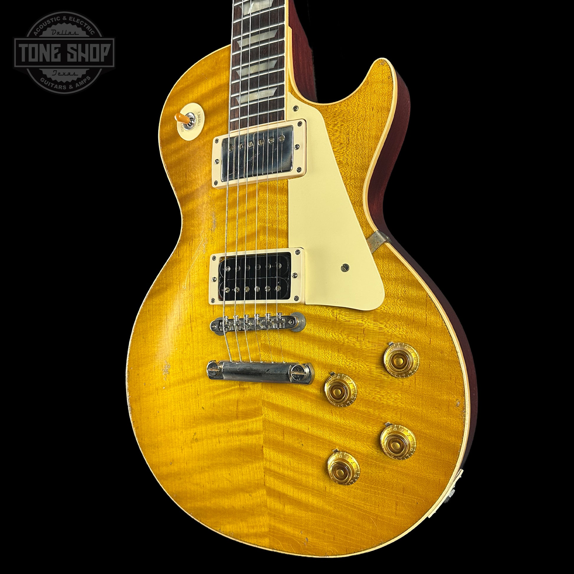 Yellow electric guitar with a black background, featuring the 'Tone Shop' logo.