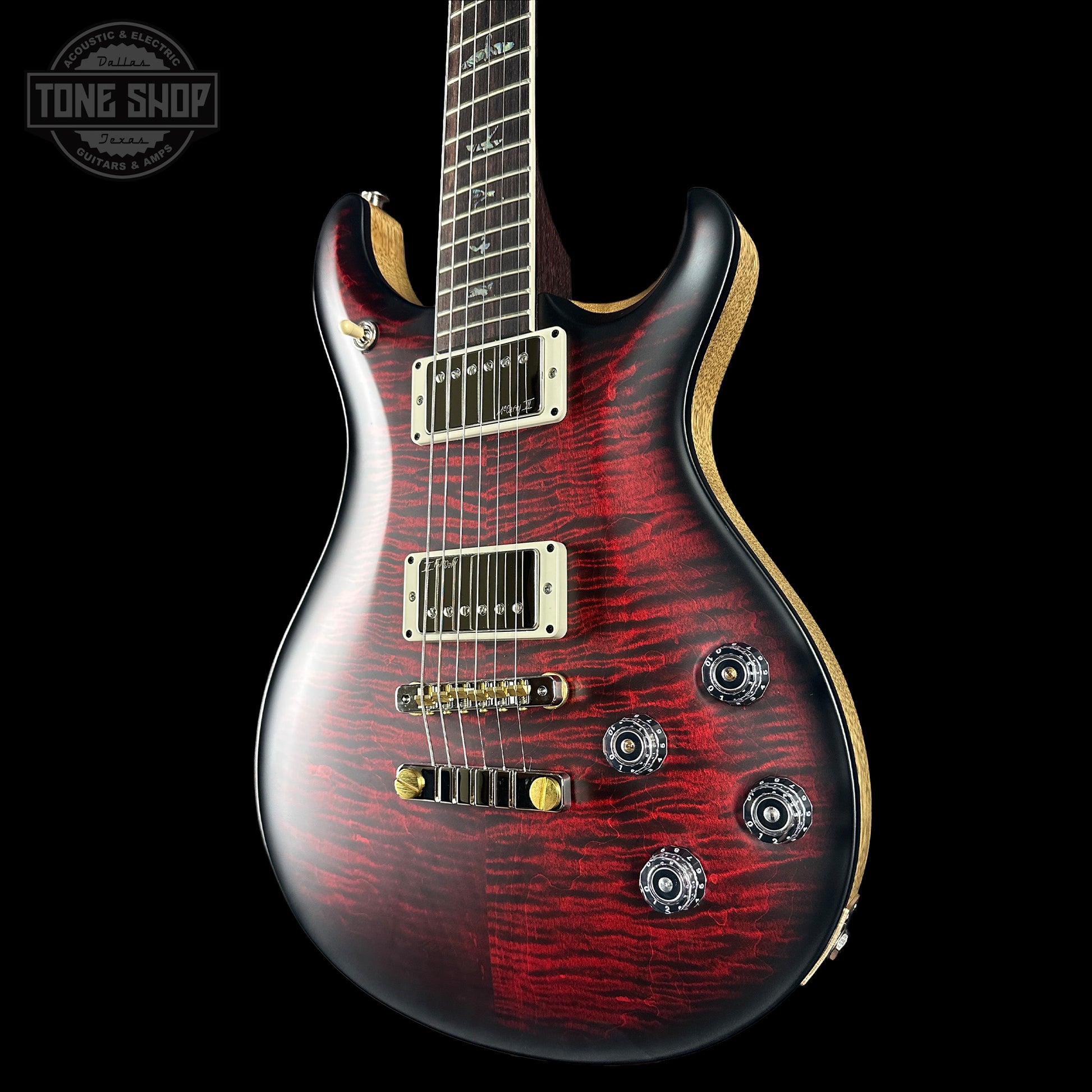 Electric guitar with a red and black finish on a black background, featuring the Tone Shop logo.