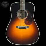 Acoustic guitar with a sunburst finish on a black background, featuring the Tone Shop logo.