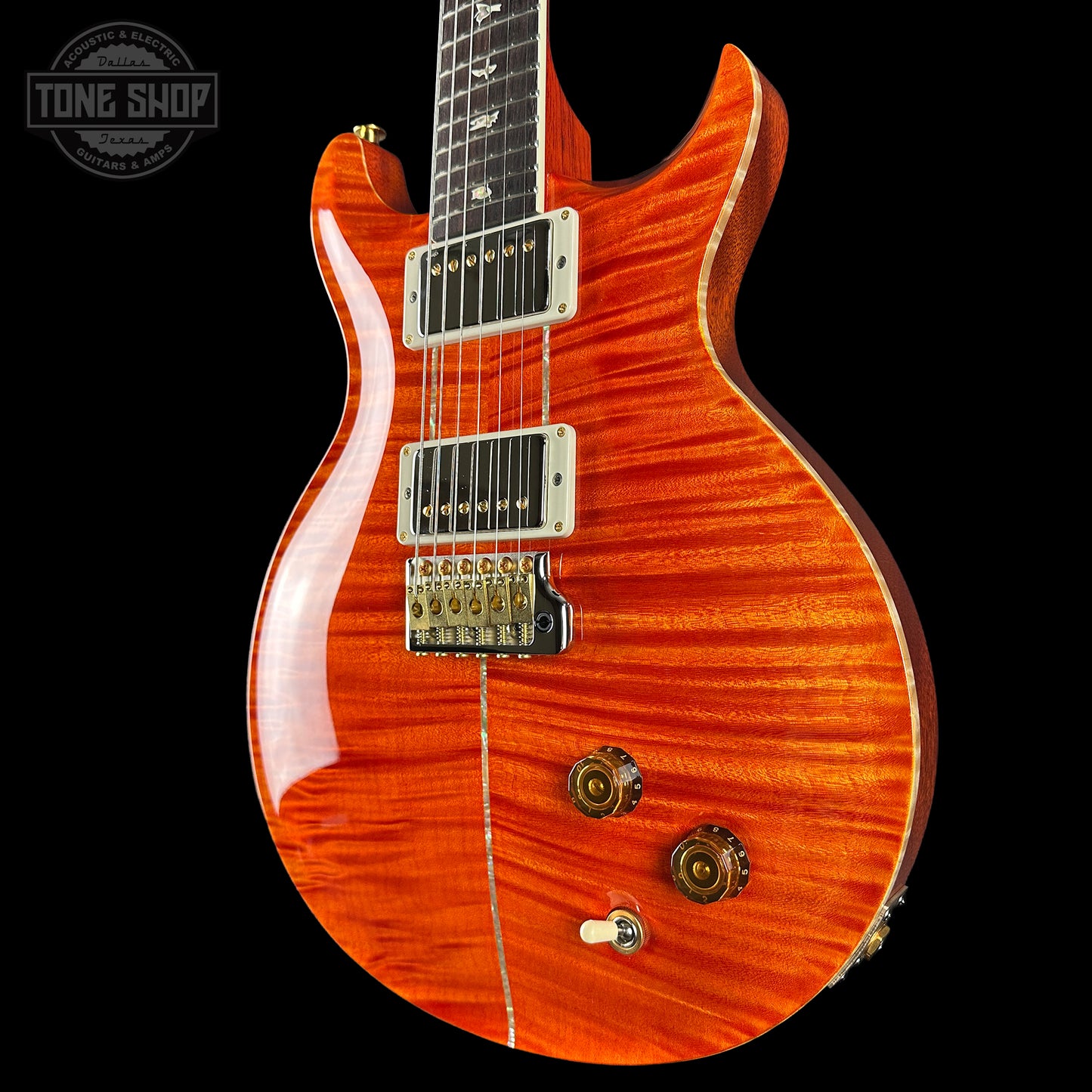 Orange electric guitar with a black background, featuring the Tone Shop logo.