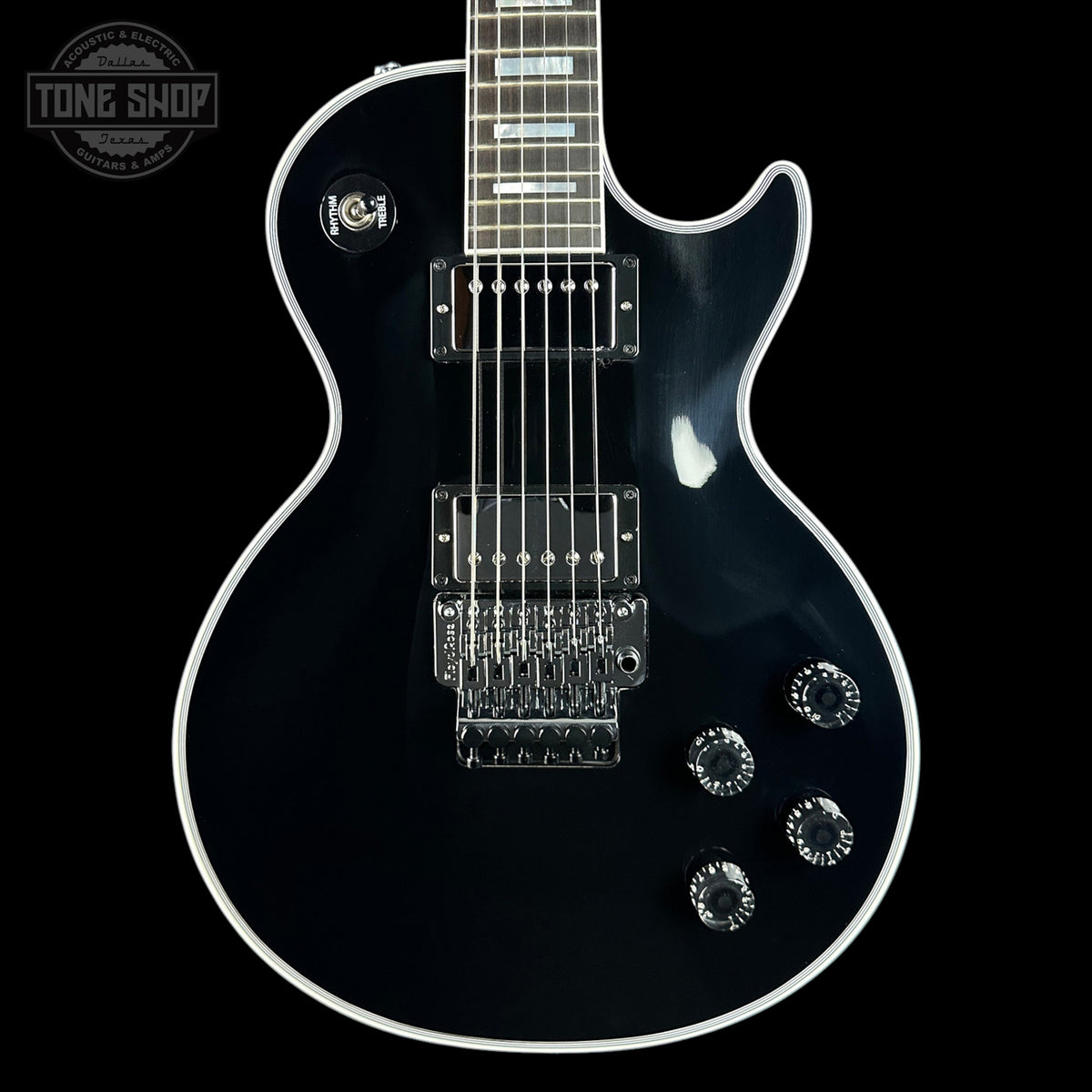 A black electric guitar with chrome hardware and white binding, shown from the front against a black background. A Tone Shop watermark is visible in the top-left corner.
