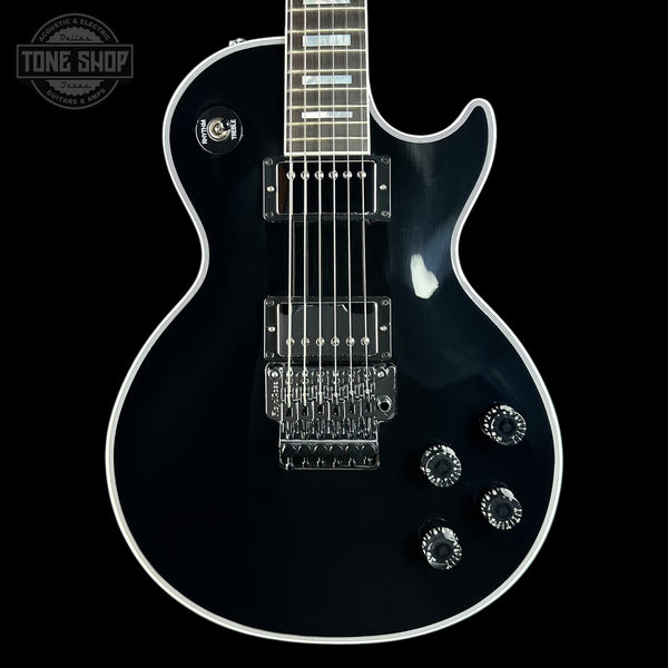 A black electric guitar with chrome hardware and white binding, shown from the front against a black background. A Tone Shop watermark is visible in the top-left corner.
