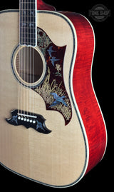 Close-up of an acoustic guitar body with a natural wood top, red flamed maple back, decorative bird inlaid pickguard, and black truss rod cover, shown against a black background with a Tong Shop watermark.