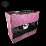 Pink guitar amplifier with crocodile texture on a black background, featuring a visible brand logo.