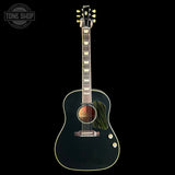 A Gibson acoustic-electric guitar with a glossy black body, gold hardware, and a distinctive green-and-black striped pickguard, shown against a solid black background with a Tone Shop watermark in the top-left corner.