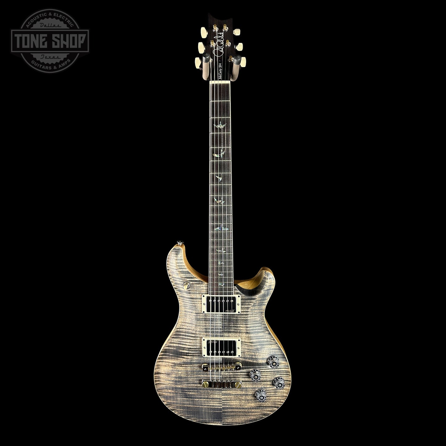 Electric guitar with a wood finish on a black background, featuring the Tone Shop logo.