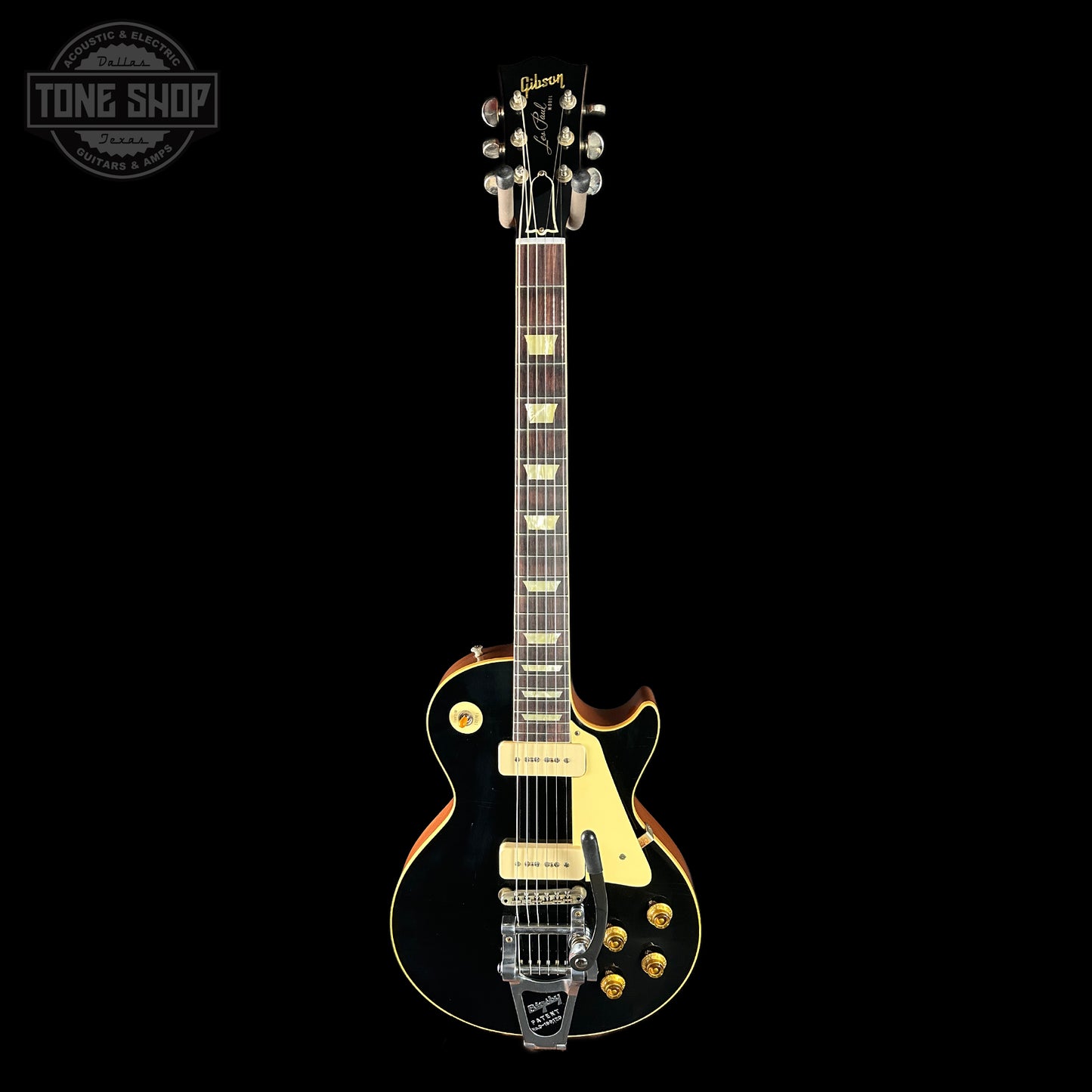 Electric guitar with a black finish and gold hardware on a black background, featuring the Gibson logo.