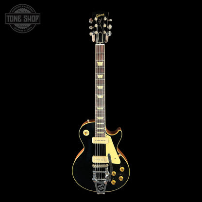 Electric guitar with a black finish and gold hardware on a black background, featuring the Gibson logo.