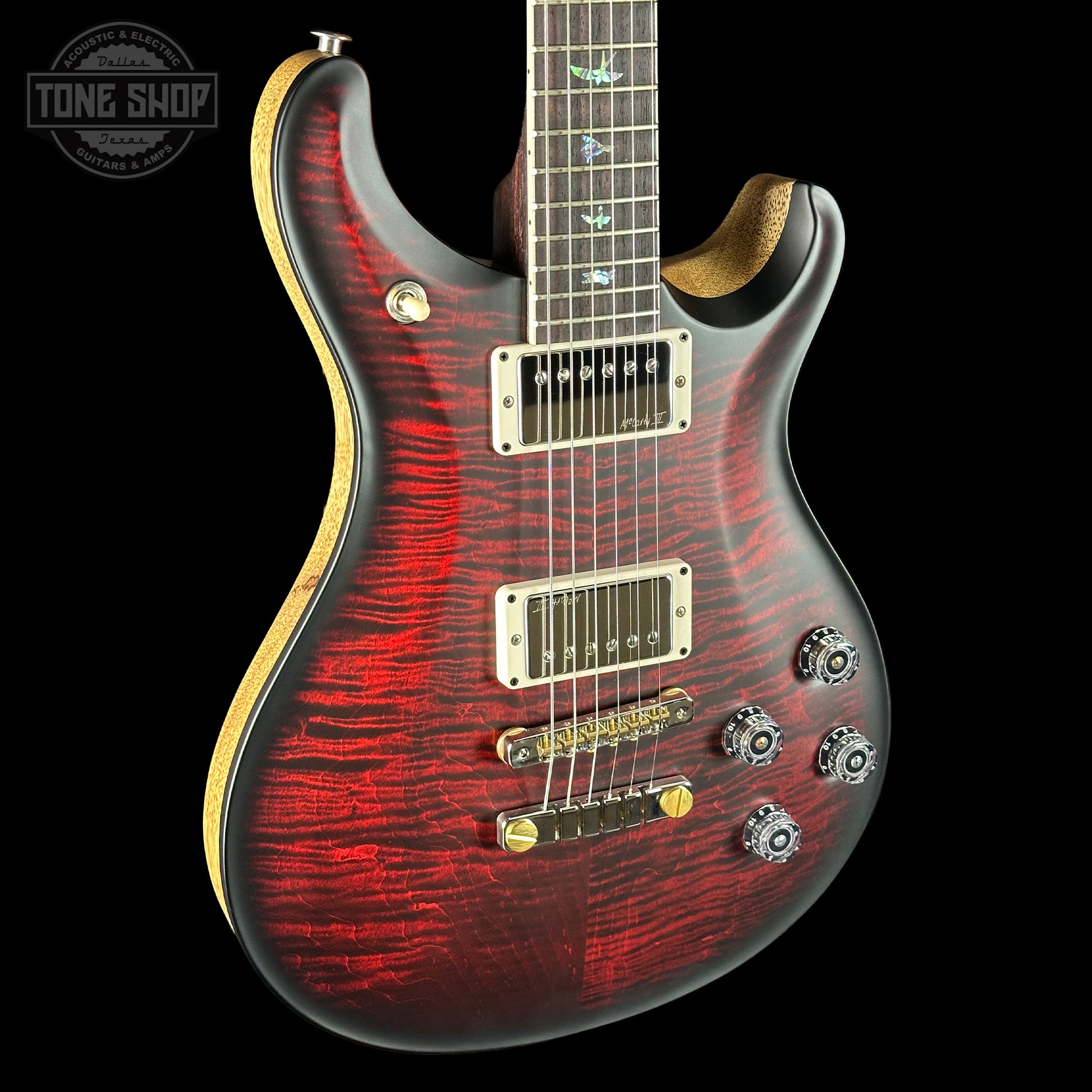 Electric guitar with a red and black pattern on a black background, featuring the Tone Shop logo.