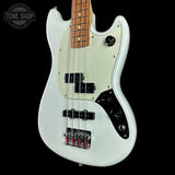 White electric bass guitar with a black pickguard on a black background, featuring the Tone Shop logo.
