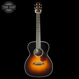 Acoustic guitar with a sunburst finish on a black background, featuring the Tone Shop logo.