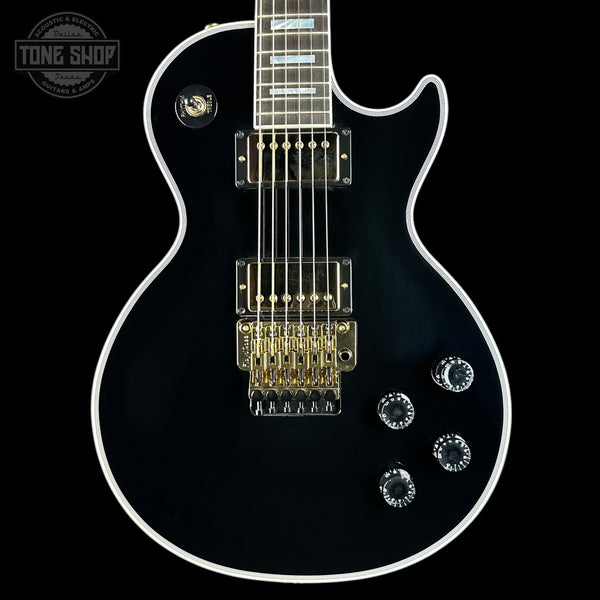 Black electric guitar with white pickguard on a black background, featuring 'Tone Shop' logo.