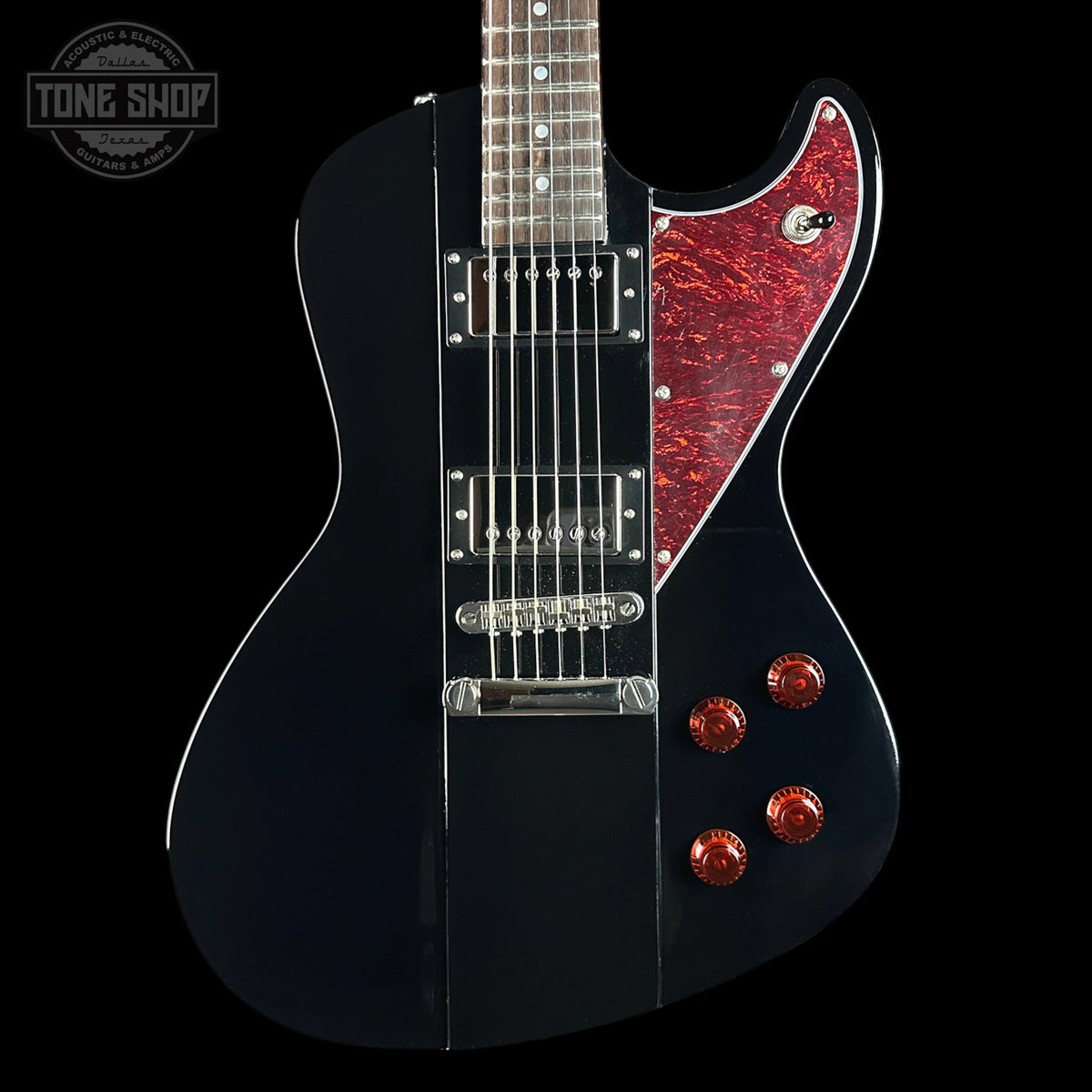 Black electric guitar with red pickguard and knobs on a black background, featuring 'Tone Shop' logo.