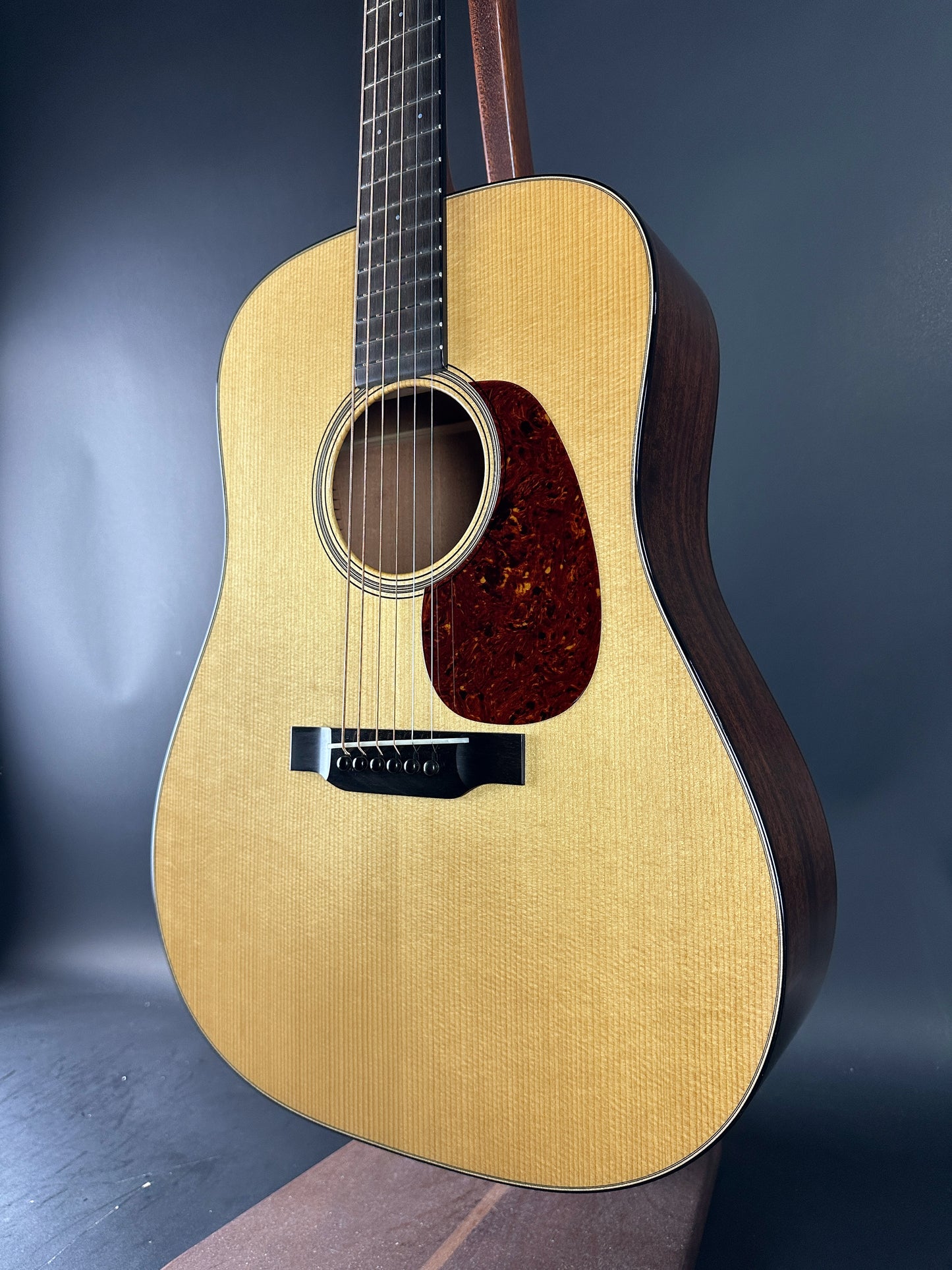 Acoustic guitar with a wooden body and dark brown neck against a gradient blue background