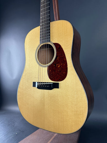 Acoustic guitar with a wooden body and dark brown neck against a gradient blue background