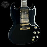 Black electric guitar with gold hardware on a black background, featuring the Tone Shop logo.