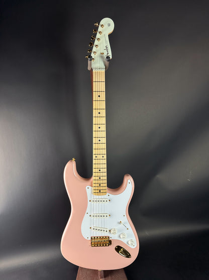 Pink electric guitar with a white pickguard on a dark background