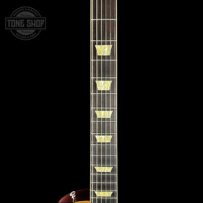 Close-up of a guitar neck with frets on a black background, featuring the Tone Shop logo.