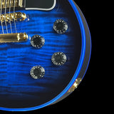 Close-up of a blue electric guitar body with black control knobs, gold hardware, and a black pickguard on a black background.