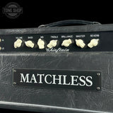 Close-up of a Matchless guitar amplifier head with a black textured cabinet, cream-colored control knobs, and a black control panel labeled with volume, bass, mid, treble, brilliance, master, and reverb. A Tone Shop watermark is visible in the top left corner.