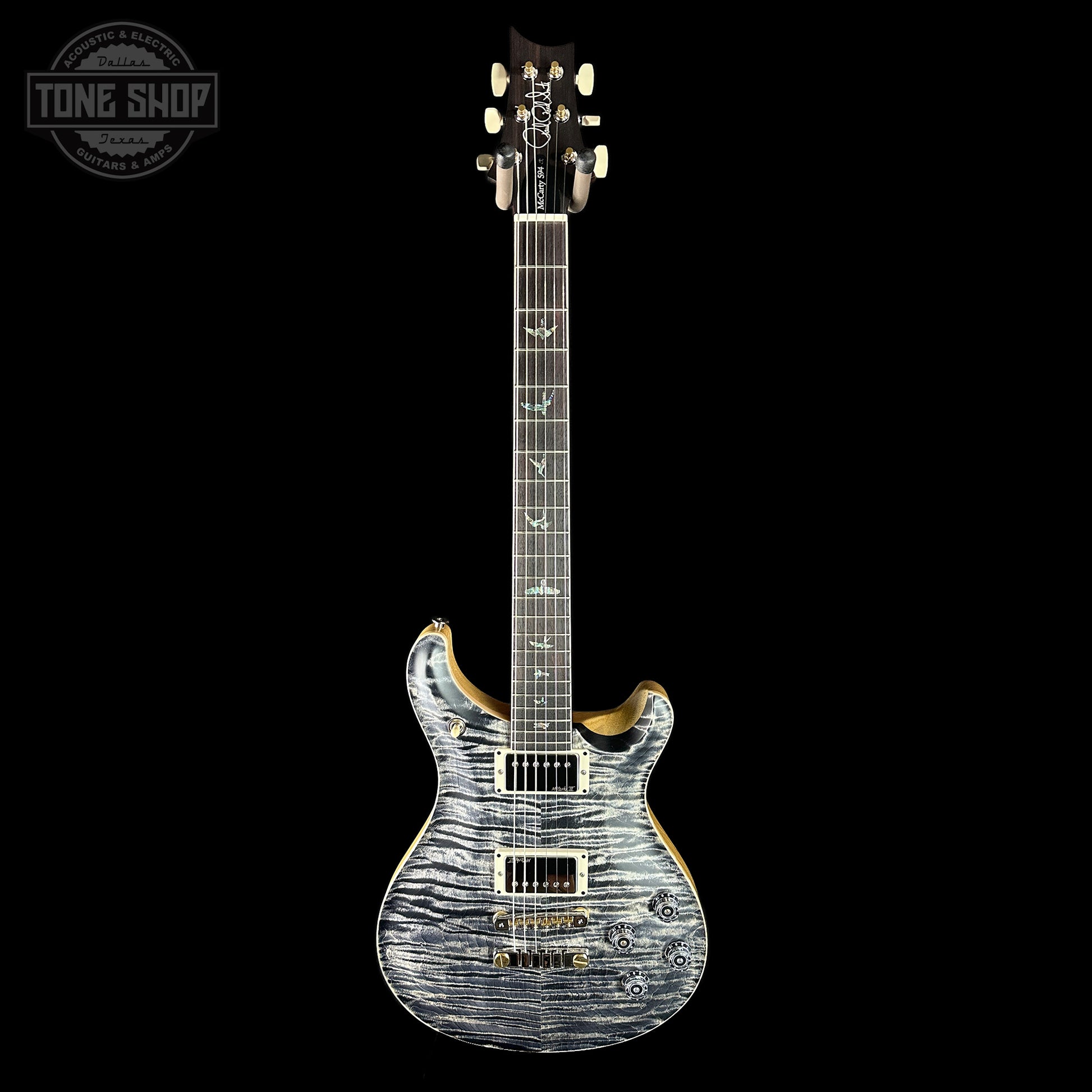 Electric guitar with a wavy wood finish on a black background, featuring the Tone Shop logo.