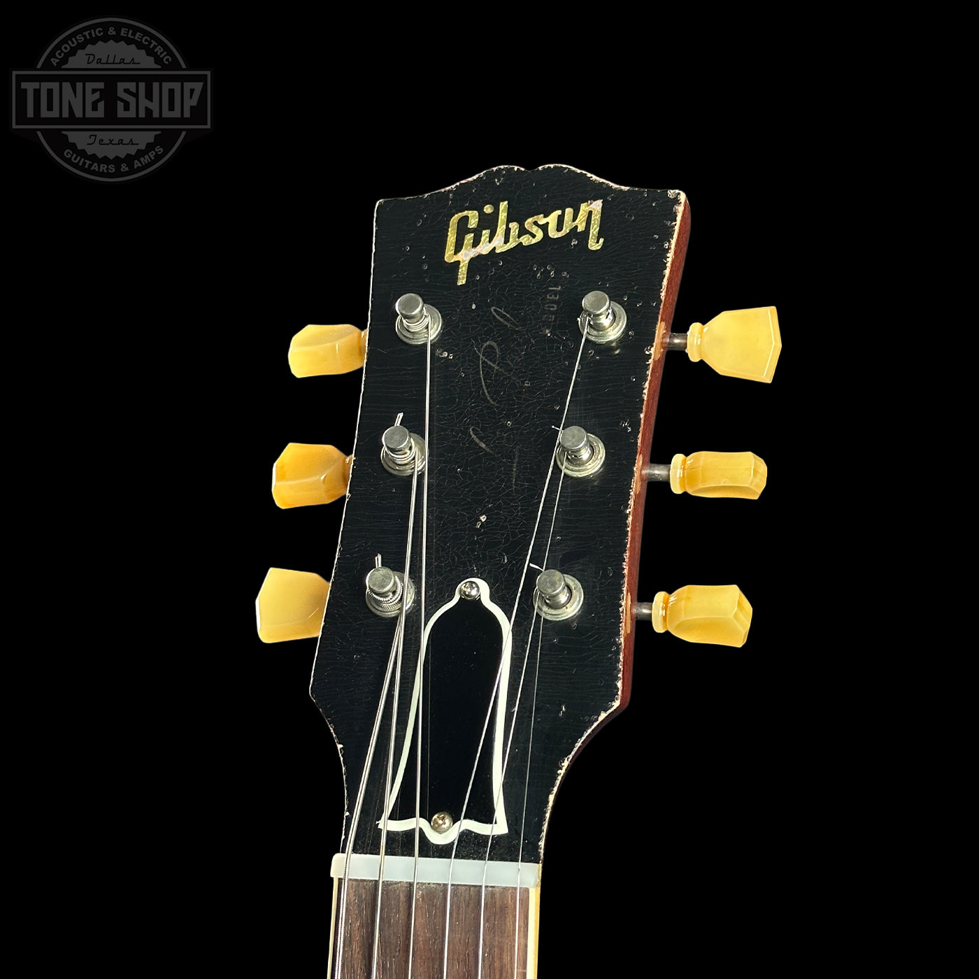 Gibson guitar headstock with yellow tuning pegs on a black background