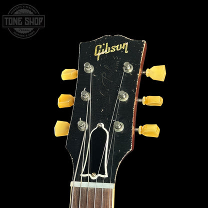 Gibson guitar headstock with yellow tuning pegs on a black background