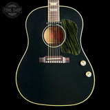 A close-up of a black acoustic guitar body with gold-toned binding, a green-and-black striped pickguard, and gold control knobs on a black background. A Tone Shop watermark is visible in the upper left corner.