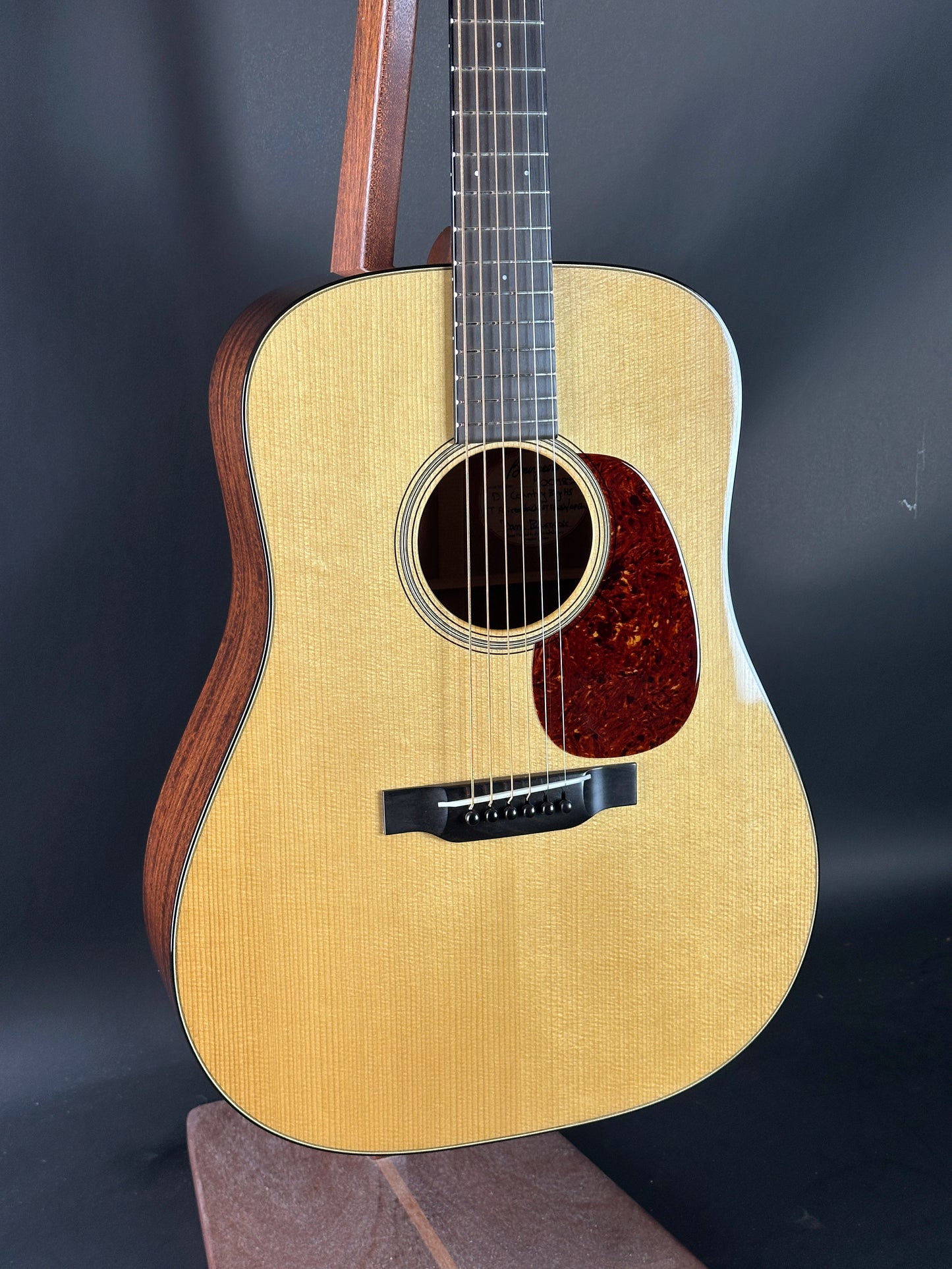 Acoustic guitar with a wooden body and dark brown neck on a dark background