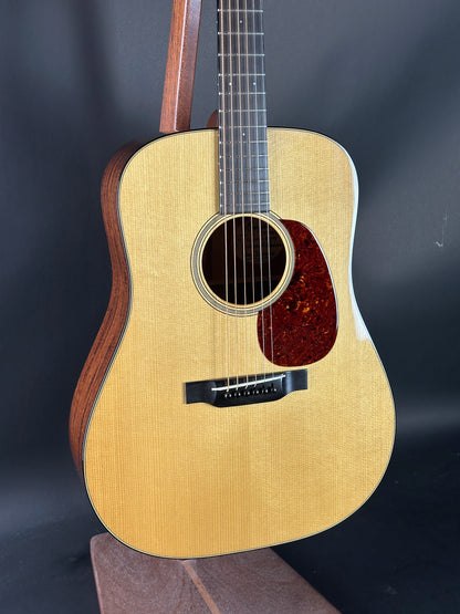 Acoustic guitar with a wooden body and dark brown neck on a dark background