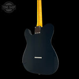 Black electric guitar with a yellow pickguard on a black background, featuring 'Tone Shop' branding.
