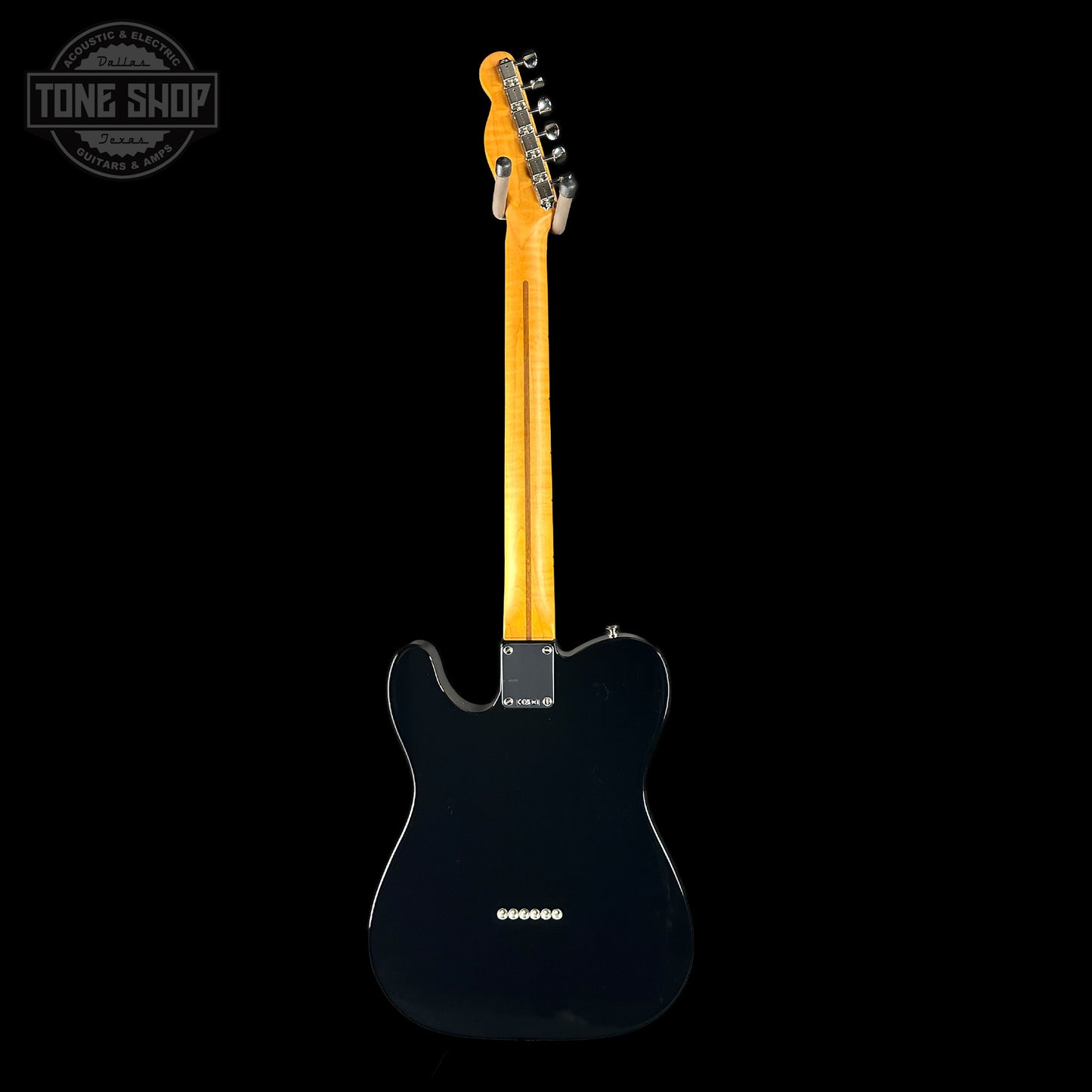 Black electric guitar with a blonde fretboard on a black background, featuring 'Tone Shop' branding.