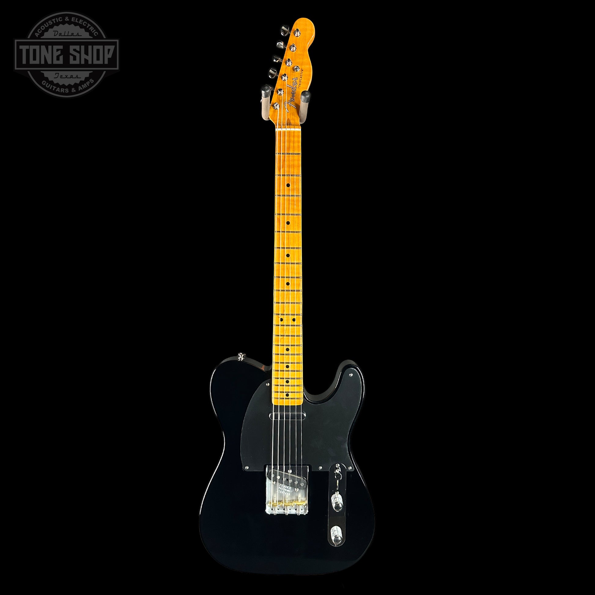 Black electric guitar with a blonde fretboard on a black background, featuring the Tone Shop logo.