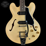 A cream-colored electric guitar with a black pickguard, chrome hardware, and gold-toned controls, shown against a solid black background. A Tone Shop watermark is visible in the top left corner.